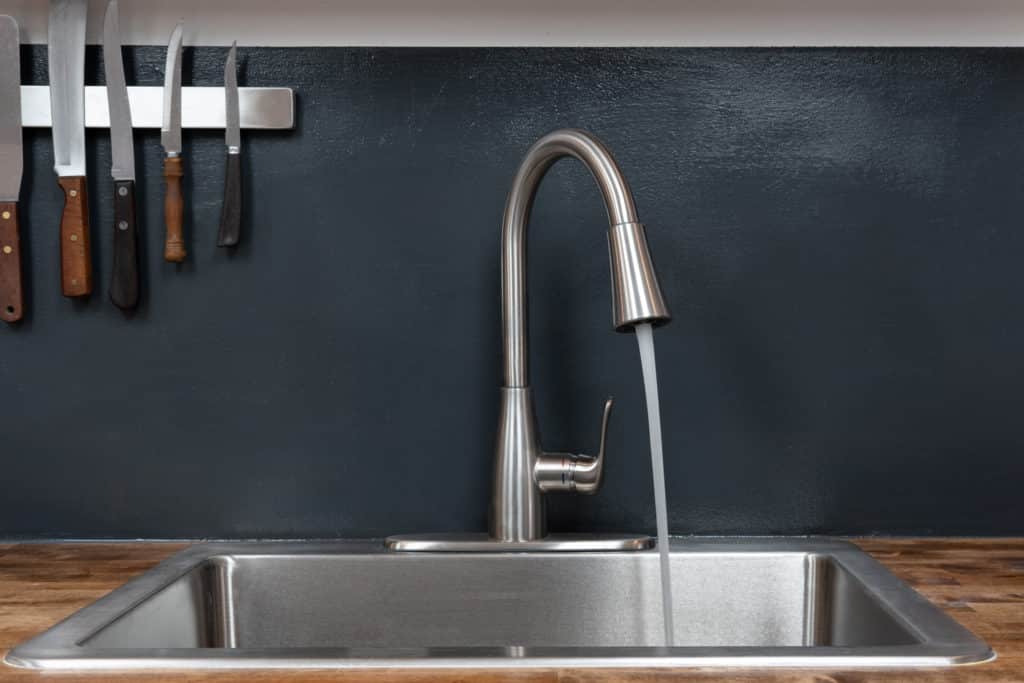 Dish sink with disc faucet with running water in a chef's kitchen