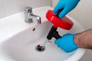 Plumber using a manual drain snake in a sink