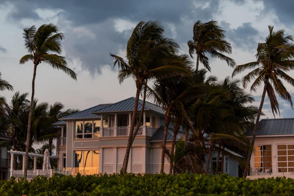 Coastal Florida home with palm trees bending in strong winds before a hurricane.