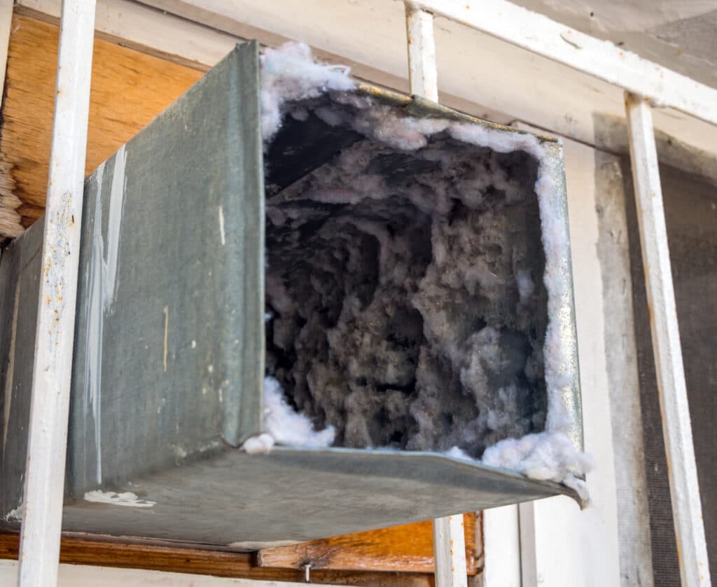 Dust and debris packed inside an HVAC air duct.
